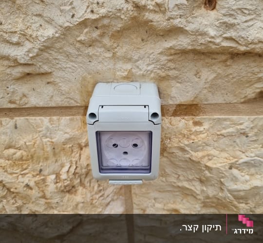 שקע חשמלי חיצוני עם כיסוי מגן על קיר אבן